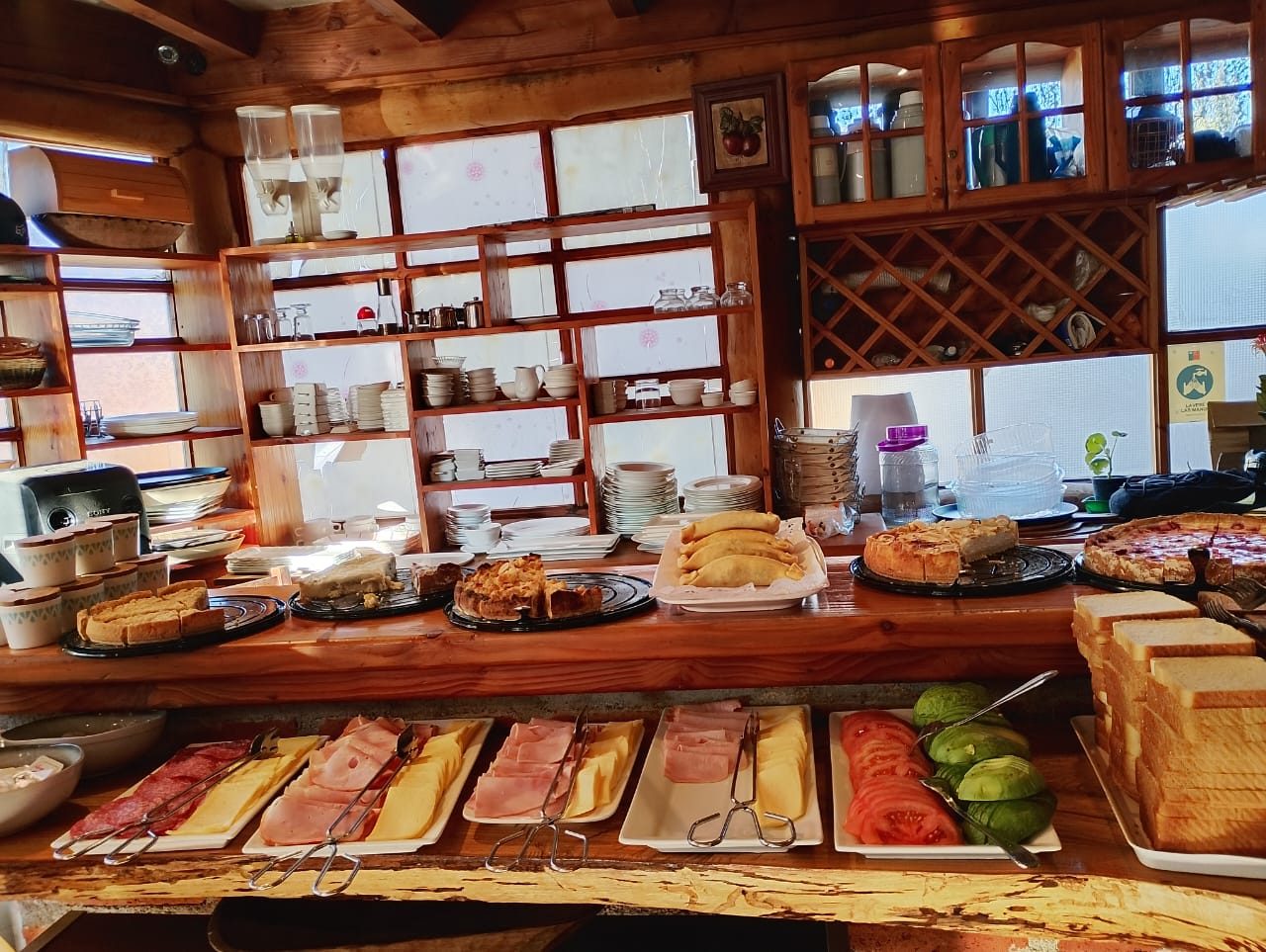 Mesa de desayuno buffet con quiches, kuchenes, empanadas, fiambres, palta y tomate